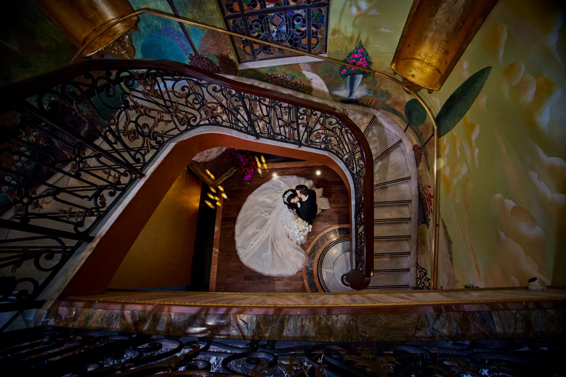 Looking down the curved staircase and iron balustrade to the couple below — The Cruz Building wedding venue, Miami, Florida