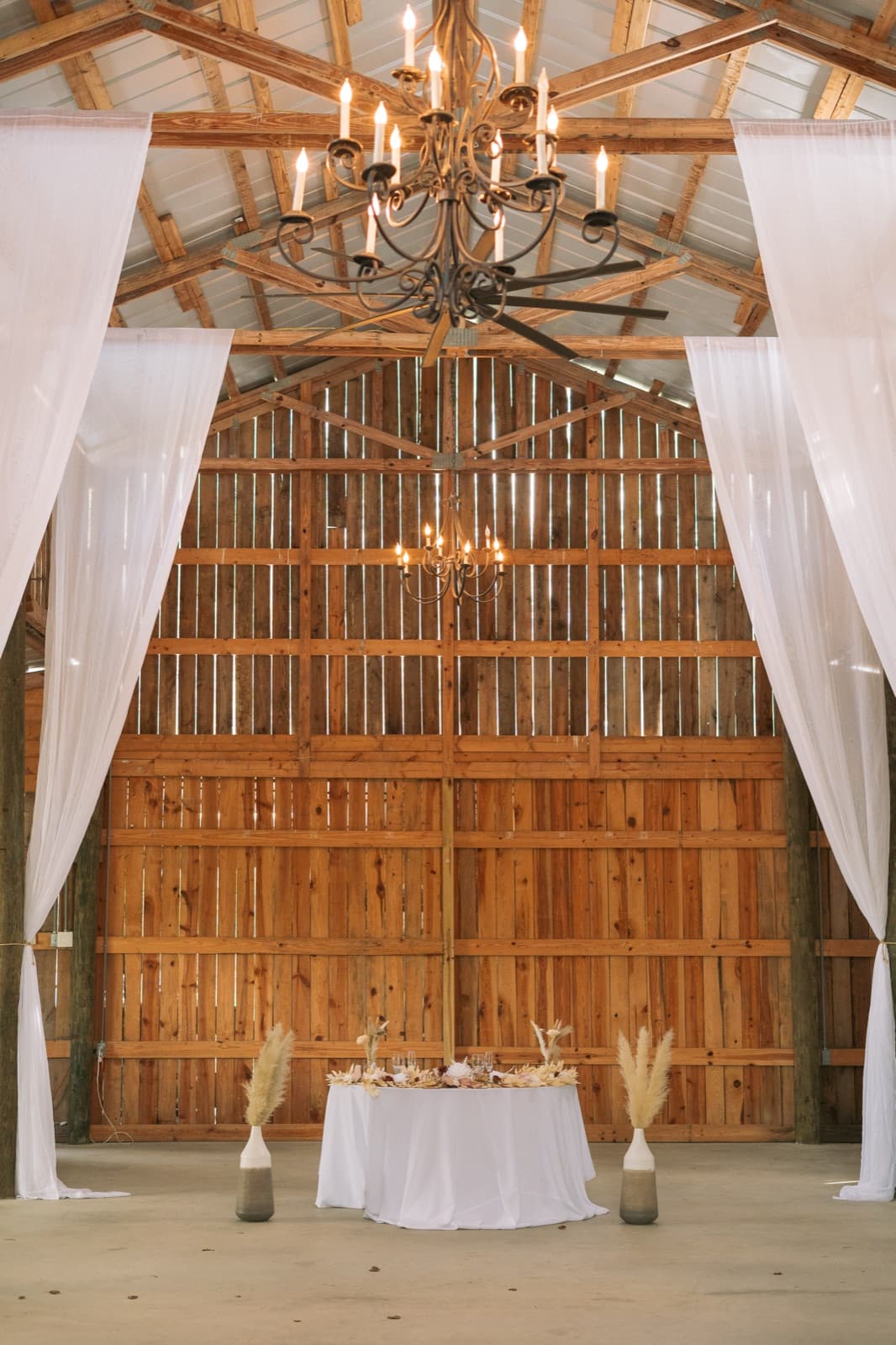 Sweetheart table beneath the barn's largest chandelier — Misty Morning Barn wedding venue, Fort Myers, Florida